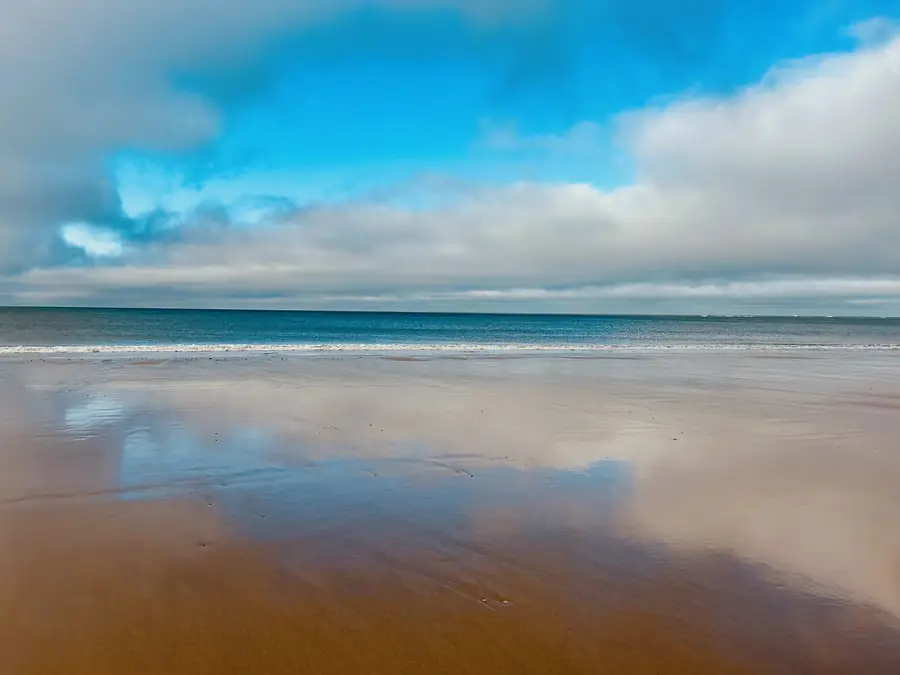 Plage à marée basse, sable réfléchissant le ciel